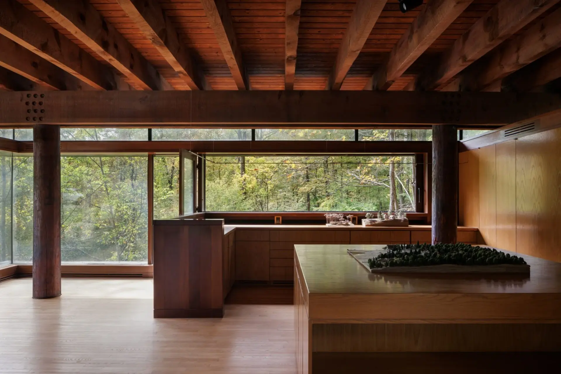 Inside, heavy timber beams and long ribbon windows frame the forest as part of the architecture. Image courtesy of Upstate Down.