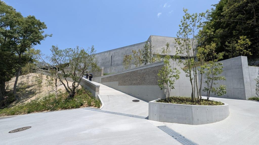 Concrete, planting and topography shape the forecourt — the transition between the ordinary world of the village and the concentrated experience of art. Photo: Benesse Art Site Naoshima.
